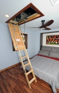 Photo showing open ceiling attic access with a ladder extending down to the floor of a bedroom. Photo courtesy of Thomas Kelsey/U.S. Department of Energy Solar Decathlon